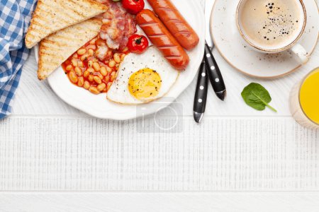 Foto de Desayuno inglés con huevos fritos, frijoles, tocino y salchichas. Café y jugo de naranja. Vista superior plano con espacio de copia - Imagen libre de derechos