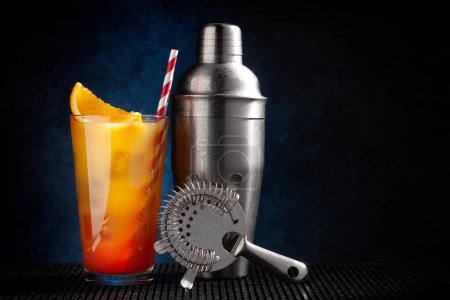 Photo for Cocktail shaker and tequila sunrise cocktail on dark background with copy space - Royalty Free Image