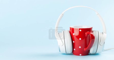 Foto de Auriculares blancos y taza de café sobre fondo azul con espacio para copiar. Podcast, audiolibro o plantilla de música - Imagen libre de derechos