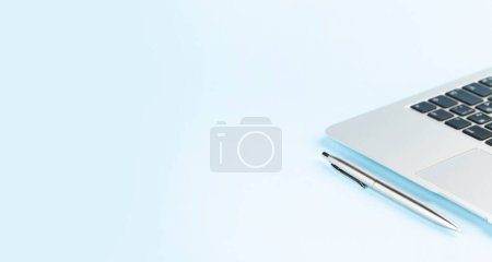 Foto de Laptop y pluma sobre fondo azul. Fondo amplio con espacio de copia. Plantilla para proyectos de oficina y trabajo - Imagen libre de derechos
