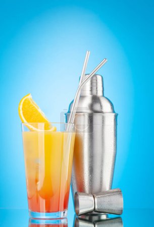 Téléchargez les photos : Cocktail shaker et tequila sunrise cocktail sur fond bleu avec espace de copie - en image libre de droit