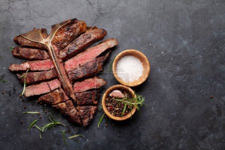 Téléchargez les photos : Steak de bœuf grillé à la porterhouse. T-bone tranché aux herbes et aux épices. Vue du dessus plat avec espace de copie - en image libre de droit