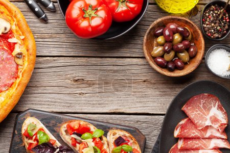Téléchargez les photos : Cuisine italienne. Pizza pepperoni, olives et toasts antipasto. Pose plate sur table en bois avec espace de copie - en image libre de droit
