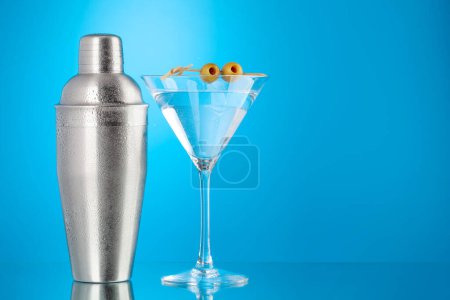 Photo for Cocktail shaker and martini cocktail on blue background with copy space - Royalty Free Image
