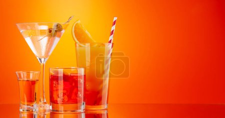 Foto de Cócteles Negroni, tequila sunrise y martini sobre fondo naranja con espacio para copiar - Imagen libre de derechos