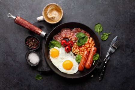 Foto de Desayuno inglés con huevos fritos, frijoles, tocino y salchichas. Vista superior plano laico - Imagen libre de derechos