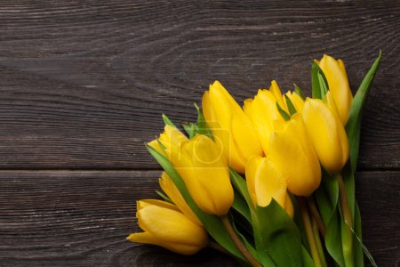 Photo for Yellow tulip flowers bouquet on wooden table. Top view flat lay with copy space - Royalty Free Image