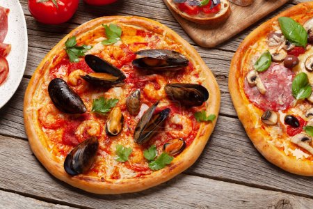 Foto de Cocina italiana. Pizza de pepperoni y mariscos, aceitunas y tostadas antipasto - Imagen libre de derechos