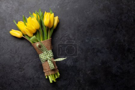 Téléchargez les photos : Bouquet de fleurs de tulipe jaune sur table en pierre. Vue du dessus plat avec espace de copie - en image libre de droit