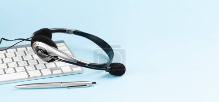 Photo for Headset over keyboard on blue background with copy space. Template for service or support - Royalty Free Image