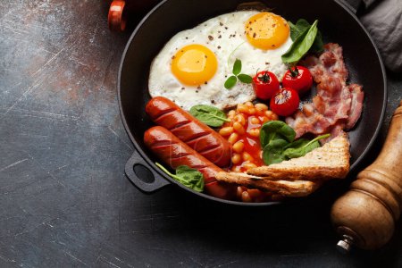 Foto de Desayuno inglés con huevos fritos, frijoles, tocino y salchichas. Vista superior con espacio de copia - Imagen libre de derechos