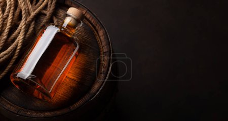 Photo for Bottle with rum, cognac or whiskey. Over old wooden barrel. Top view flat lay with copy space - Royalty Free Image