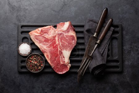 Photo for Porterhouse or T-bone raw beef steak with herbs and spices over grill. Top view flat lay - Royalty Free Image