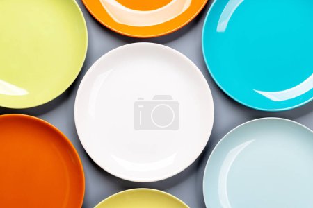 Photo for Different clean colorful plates on grey background. Flat lay with copy space - Royalty Free Image