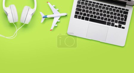 Foto de Concepto de viaje y reserva en línea. Ordenador portátil y avión en escritorio verde con espacio para copiar - Imagen libre de derechos