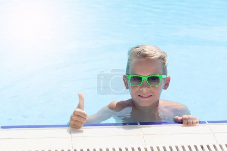 Foto de Niño con pulgares arriba relajándose en la piscina. Con espacio de copia - Imagen libre de derechos