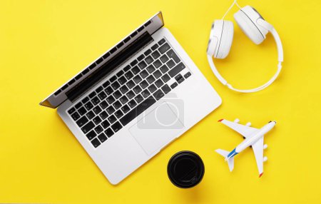 Foto de Concepto de viaje y reserva en línea. Ordenador portátil y avión en escritorio amarillo. Puesta plana - Imagen libre de derechos