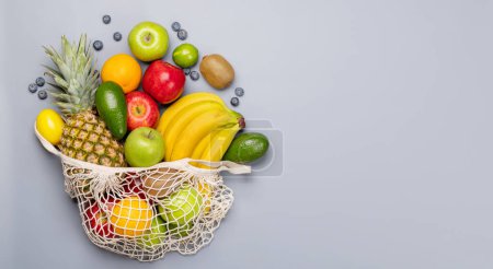 Photo for Shopping mesh bag full of healthy fruits food on grey background. Flat lay with copy space - Royalty Free Image