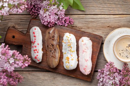 Téléchargez les photos : Dessert et café Eclair. Sur table en bois avec fleurs lilas. Vue du dessus plat lay - en image libre de droit