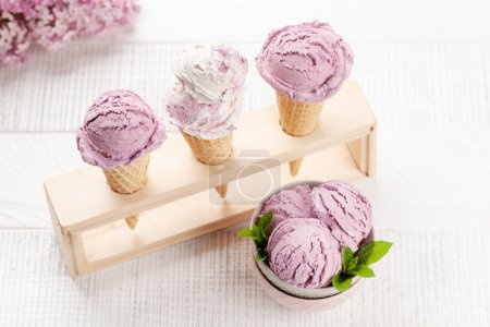 Photo for Berry ice cream sundae in waffle cones and lilac flowers - Royalty Free Image