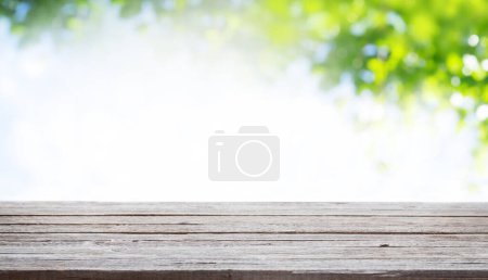 Téléchargez les photos : Table en bois avec espace de copie pour votre produit et bokeh ensoleillé vert. Modèle extérieur - en image libre de droit