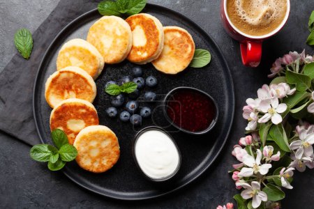 Foto de Panqueques caseros con mermelada de bayas, crema agria y bayas. Desayuno con café. Vista superior plano laico - Imagen libre de derechos