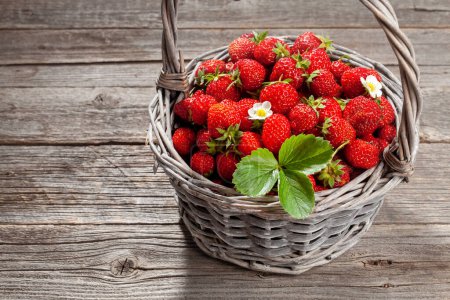 Photo for Ripe strawberries in basket on wooden table - Royalty Free Image