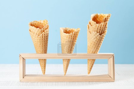 Téléchargez les photos : Cônes de gaufres à la crème glacée vides dans un stand en bois - en image libre de droit