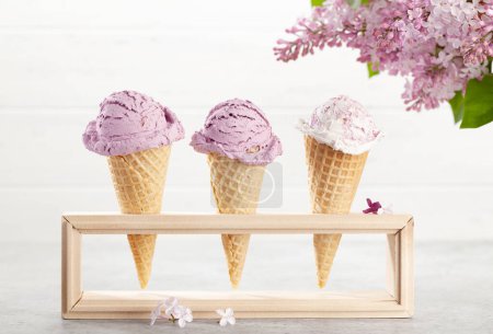 Foto de Varios helados en conos de gofre y flores lila - Imagen libre de derechos