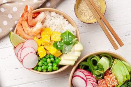 Poke bowls with shrimps, salmon, avocado and mango. Traditional hawaiian meal. Top view flat lay