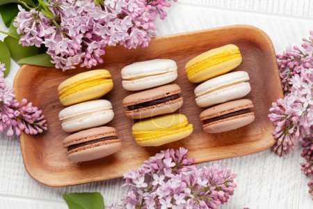 Téléchargez les photos : Divers biscuits au macaron. Sur table en bois avec fleurs lilas. Vue du dessus plat lay - en image libre de droit