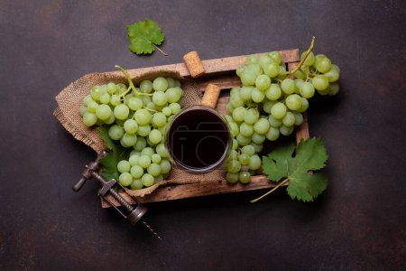 Foto de Copa de vino tinto, sacacorchos vintage y uva blanca. Vista superior plano laico - Imagen libre de derechos