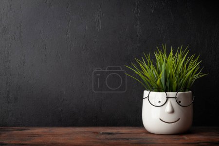 Photo for Potted plant with glasses on wooden table and blackboard for copy space. School and education template - Royalty Free Image