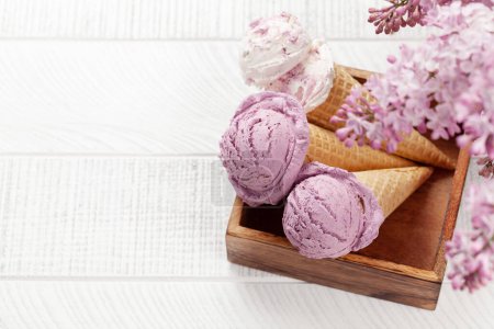 Téléchargez les photos : Crème glacée aux baies sundae aux cônes de gaufres et fleurs lilas - en image libre de droit