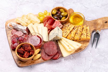 Foto de Antipasto con jamón, salami, galletas saladas, queso, aceitunas y nueces - Imagen libre de derechos
