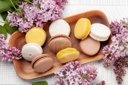 Photo for Various macaroon cookies. On wooden table with lilac flowers. Top view flat lay - Royalty Free Image
