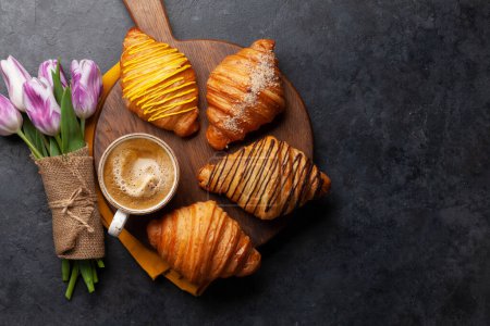 Foto de Varios croissants y café sobre tabla de madera y ramo de tulipanes. Desayuno francés. Vista superior plano con espacio de copia - Imagen libre de derechos