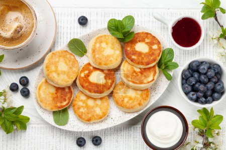 Foto de Panqueques caseros con mermelada de bayas, crema agria y bayas. Desayuno con café. Vista superior plano laico - Imagen libre de derechos