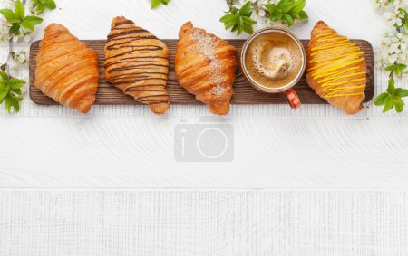Foto de Varios croissants y taza de café sobre tabla de madera. Desayuno francés. Vista superior plano con espacio de copia - Imagen libre de derechos