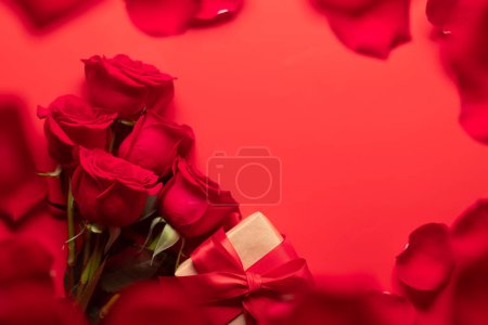 Foto de Tarjeta de San Valentín con caja de regalo y flores rosadas. Sobre fondo rojo con espacio para tus saludos. Puesta plana - Imagen libre de derechos
