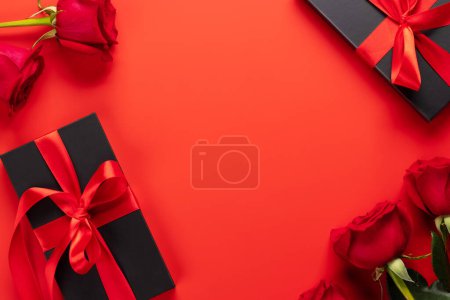 Téléchargez les photos : Carte Saint Valentin avec coffrets cadeaux et fleurs roses. Sur fond rouge avec espace pour vos salutations - en image libre de droit