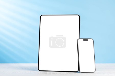 Téléchargez les photos : Tablette et smartphone avec écran blanc sur le bureau d'affaires. Espace de travail avec lumière ensoleillée et espace de copie - en image libre de droit