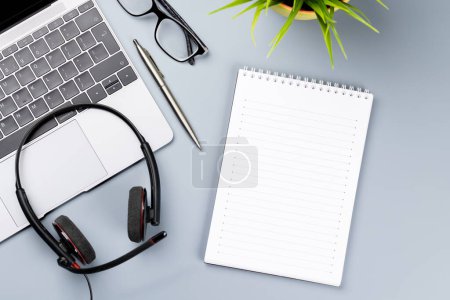 Foto de Escritorio de oficina de vista superior con computadora portátil, suministros de oficina y auriculares. Espacio de trabajo con luz soleada y espacio de copia - Imagen libre de derechos