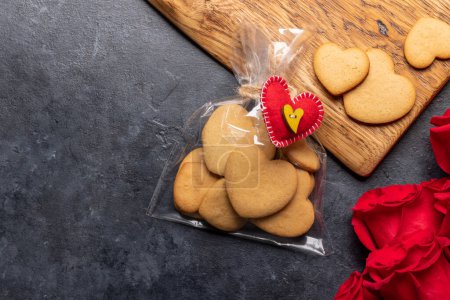 Foto de Tarjeta de San Valentín con galletas en forma de corazón y flores de rosas. Piso con espacio de copia - Imagen libre de derechos