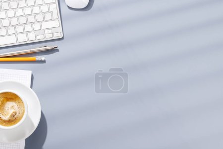 Foto de Escritorio de oficina de vista superior con teclado, suministros de oficina y café. Espacio de trabajo plano con luz soleada y espacio de copia - Imagen libre de derechos
