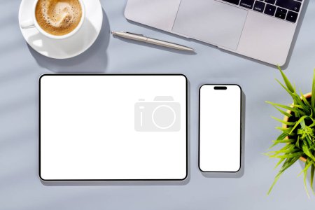 Téléchargez les photos : Tablette et smartphone avec écran blanc sur le bureau d'affaires. Espace de travail plat avec lumière ensoleillée et espace de copie - en image libre de droit
