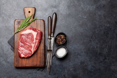 Photo for Raw ribeye steak on cutting board. Barbecue cooking. Flat lay with copy space - Royalty Free Image