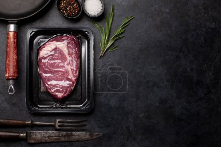 Vacuum packed beef steak. Ribeye steak and cooking utensils. Top view flat lay with copy space