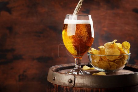 Photo for Beer glass and potato chips on wooden barrel. With copy space - Royalty Free Image