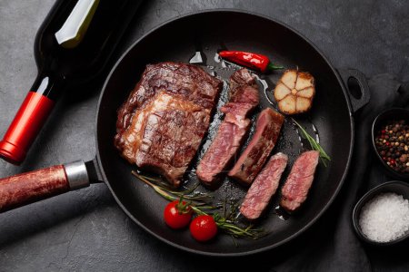Photo for Grilled ribeye beef steak in frying pan with herbs and spices. Flat lay - Royalty Free Image